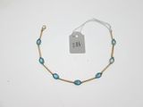 un bracelet en or orné de perles de verre bleues et d'une étiquette de prix