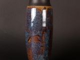 a blue and brown vase on a black surface