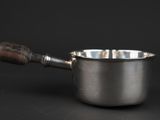 a silver saucepan with a wooden handle on a black background