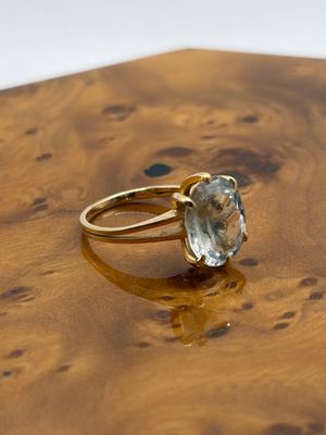 yellow gold ring with a blue topaz stone on top of a wooden table