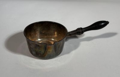 a small metal cup with a wooden handle on a table