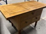 une table en bois munie de tiroirs, dans un entrepôt