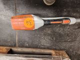 un aspirateur sans fil orange et blanc posé par terre