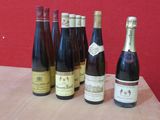 Plusieurs bouteilles de vin sont alignées sur une table devant un mur rouge.