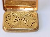 a small gold box with a gold design on it