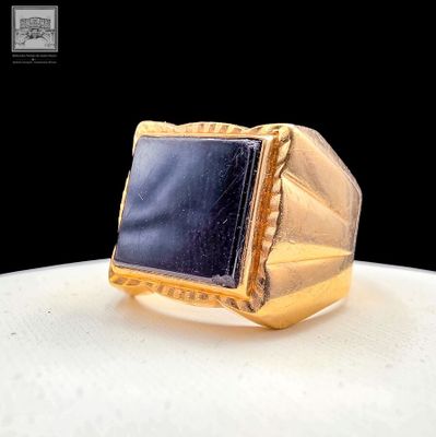 yellow gold ring with a black stone in the center on a white surface