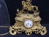 a gold clock with a glass dome next to it