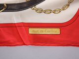 a red and white scarf with a gold chain on it
