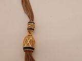 a close up of a gold and black tassel on a white surface