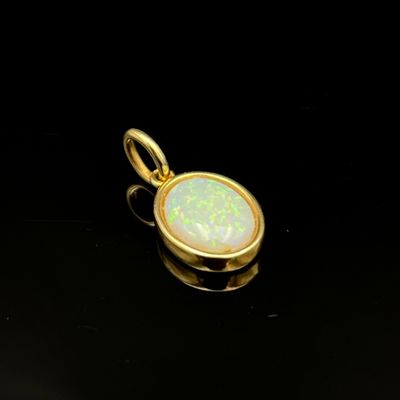 un pendentif en or orné d'une pierre oplite blanche au centre