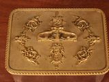 a gold box on a wooden table with a clock on it