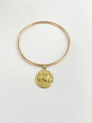 un bracelet rigide en or orné d'une breloque en forme de pièce de monnaie