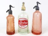 trois flacons contenant du savon et de la lotion, posés sur une surface blanche