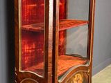 an antique wooden display cabinet with a red glass door