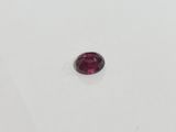 a close up of a red garnet stone on a white surface