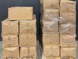 des cartons empilés sur des palettes dans un entrepôt, avec un tableau noir en arrière-plan