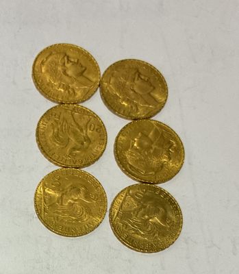 six gold coins sitting on top of each other on a white surface