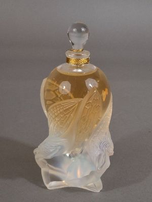 une bouteille en verre ornée d'un oiseau, posée sur une table