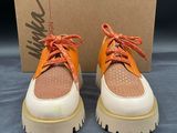 une paire de baskets orange et blanches avec une boîte en arrière-plan