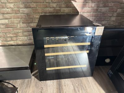 a wine cooler sitting on the floor next to a brick wall