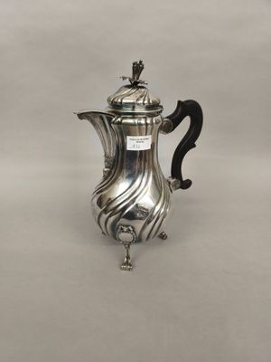 une cafetière en argent avec une anse, posée sur une surface blanche