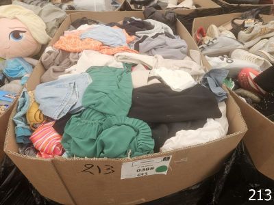 a cardboard box filled with lots of clothes and a stuffed animal