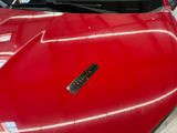 a red car that has a sticker on the hood