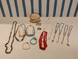 many necklaces and bracelets laid out on a table