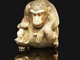 an ivory nets sculpture of a monkey holding a baby monkey