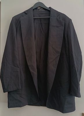 black blazer jacket hanging on a hanger on a wall