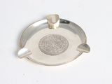 a silver ashtray with a silver medallion on it