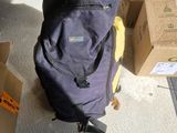 a purple backpack sitting on the floor next to a pile of boxes