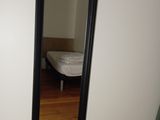 a mirror in the corner of a room with a bed in the background