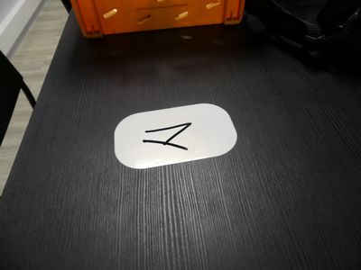 un autocollant blanc posé sur une table noire, sur lequel figure un petit « z »