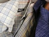 three shirts hanging on a rail in a closet