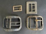 three antique belt buckles and a metal belt buckle on a table