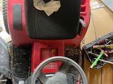 a red lawn mower sitting on the ground next to a pile of junk