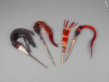 trois plumes de couleurs différentes sont disposées en ligne sur une surface grise