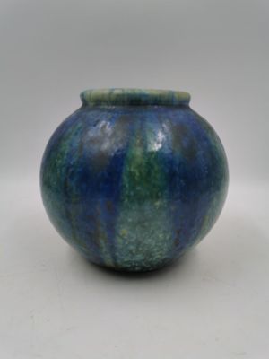 un vase bleu et vert posé sur une surface blanche