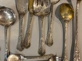 many silver spoons and spoon spoons hanging on a wall