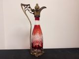 un vase rouge et blanc muni d'une poignée en métal, posé sur une table