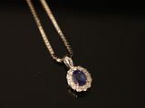 a close up of a blue sapphire and diamond pendant on a chain