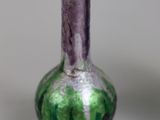 a green and purple vase sitting on a table