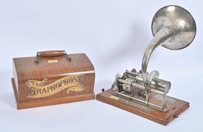 un gramophone argenté posé sur un socle en bois, à côté d'une boîte en bois