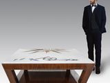 a man standing next to a coffee table with a design on it