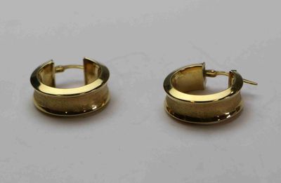 une paire de boucles d'oreilles en or sur fond blanc