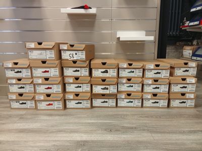 a pile of boxes of shoes sitting on top of a wooden floor