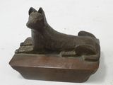 statue of a cat laying on a wooden block on a white surface