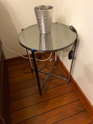 a glass table with a metal vase on top of it