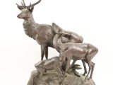 bronze sculpture of a stag and three deers on a rock